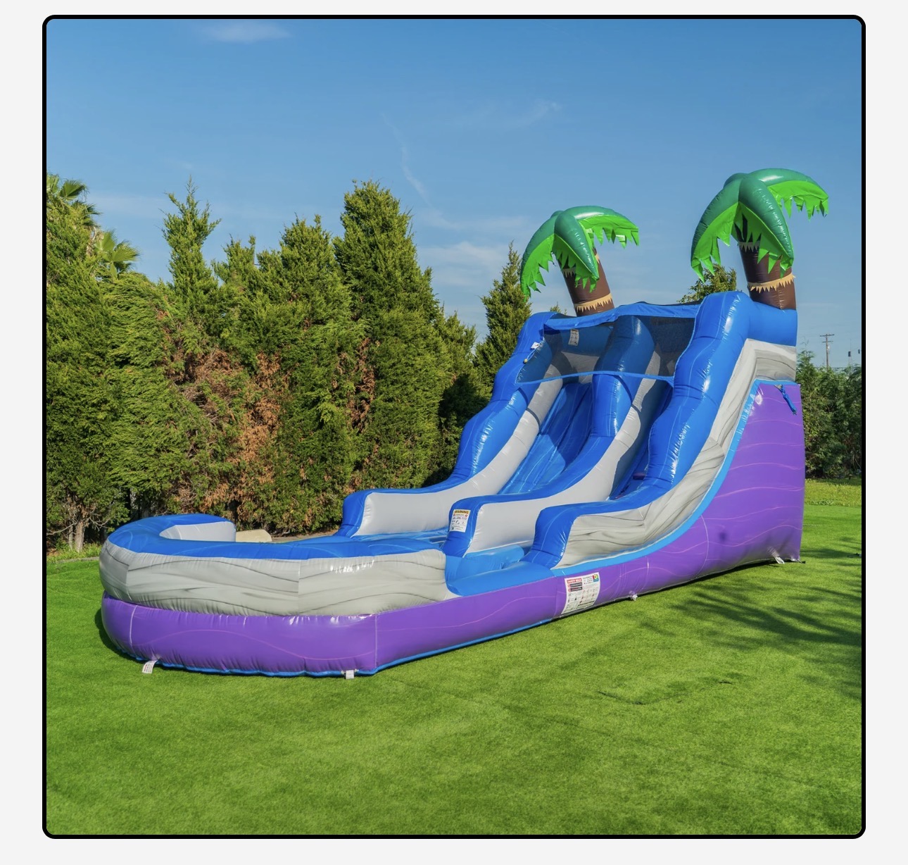 Tropical purple and blue inflatable water slide with palm trees and splash pool